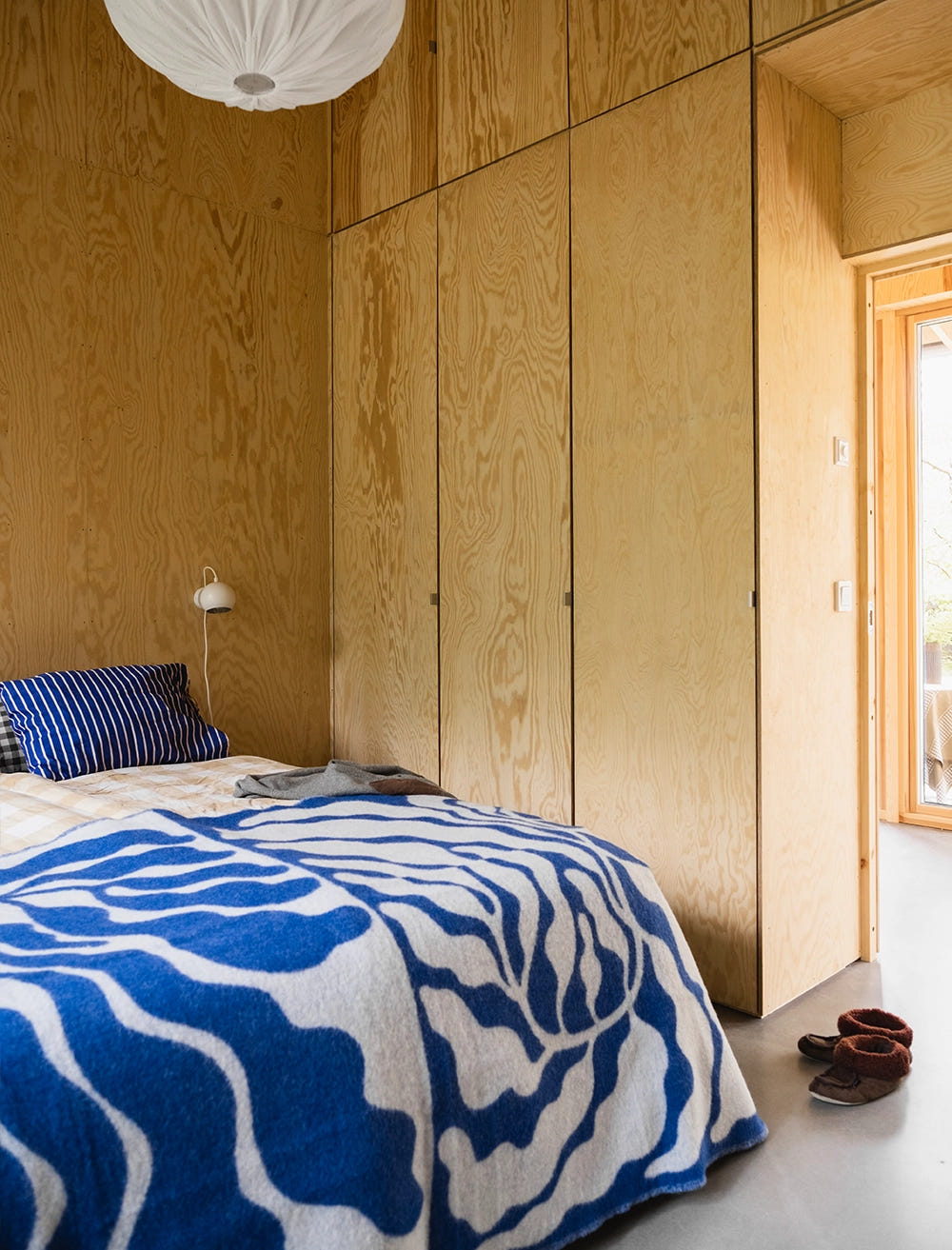 Leaves ullpläd med stormönstrat bladmönster i blått och vitt, här som överlast på säng