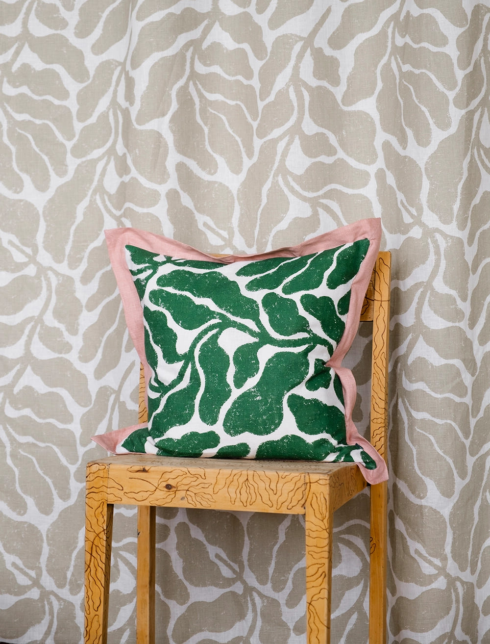 Kuddfodral med stort grönt bladmönster och en rosa volang runt omkring